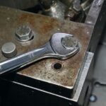 A Beta Tools combination wrench tightening a large hex bolt on a rusted metal surface, showing its strength and durability in industrial conditions. Get it at Wrenchers.com.
