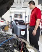 Automotive technician operating the Robinair 34788NI-H A/C service machine during vehicle HVAC diagnostics, highlighting its user-friendly controls and professional-grade performance