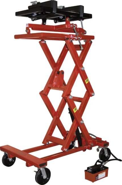 Red hydraulic transmission jack with a scissor-lift design, adjustable saddle, locking brackets, and four swivel casters, shown fully raised with the foot-operated pump attached