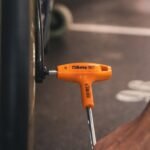 A Beta Tools 3-Offset Hexagon Key Wrench in use on a black metal frame, demonstrating professional torque and comfort. Get it at Wrenchers.com.