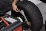 Technician pulling the data entry arm against a mounted wheel to input rim measurements.