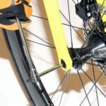 Close-up of a mechanic using a Beta Tools T-handle wrench to tighten a front axle bolt on a yellow road bike with disc brakes. Get it at Wrenchers.com.