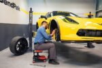 Brake replacement performed under yellow Corvette using MaxJax M7K garage car lift.