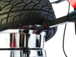 Bead roller detail on the Coats APX-90 tire changer applying controlled pressure to guide stiff sidewalls during mounting and demounting operations