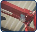 Close-up of an overhead crossbar on a red automotive lift showing the mounted safety limit switch and wiring harness