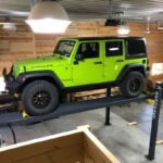 Jeep on BendPak four post home storage lift. Safe, space-saving vehicle stacking solution.