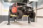 Jeep Wrangler raised on MaxJax M7K two-post portable lift inside workshop.