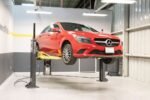 Mercedes sedan lifted on MaxJax M7K portable two-post car lift inside garage.