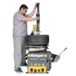 Operator using the Ranger R76LT tire changer to service a stacked tire assembly, demonstrating ergonomic controls and hands-on workflow