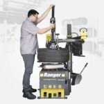 Shop operator mounting a performance tire on the Ranger R76ATR, demonstrating its power-assist arm and ergonomic workflow for high-volume environments