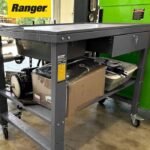 Ranger RWB-1TD teardown workbench in a real customer shop loaded with tools, boxes, and equipment on the shelf beneath the basin